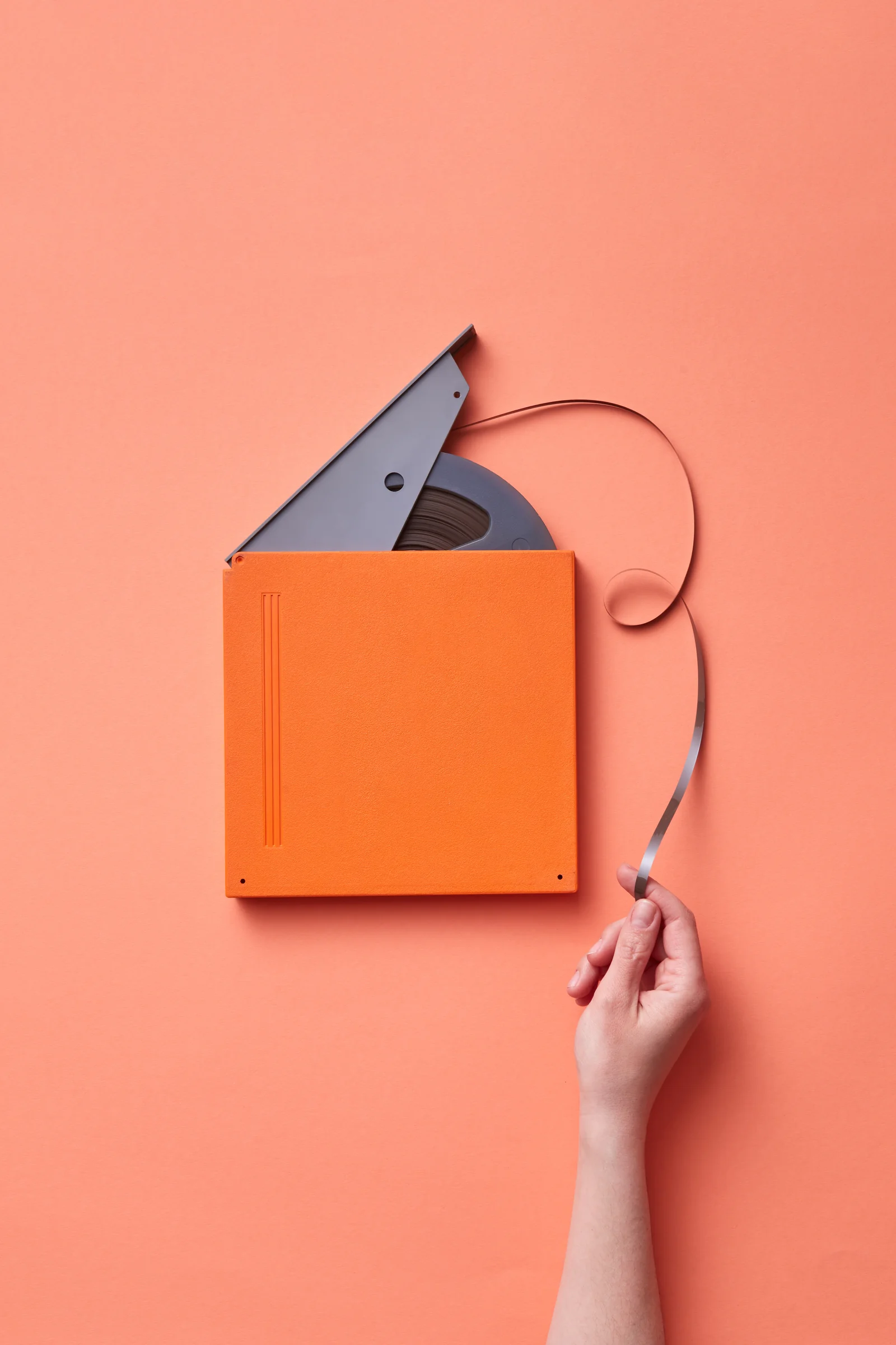 Hand pulling cine film from a reel case — inspecting Super 8, Standard 8 and other gauges before scanning