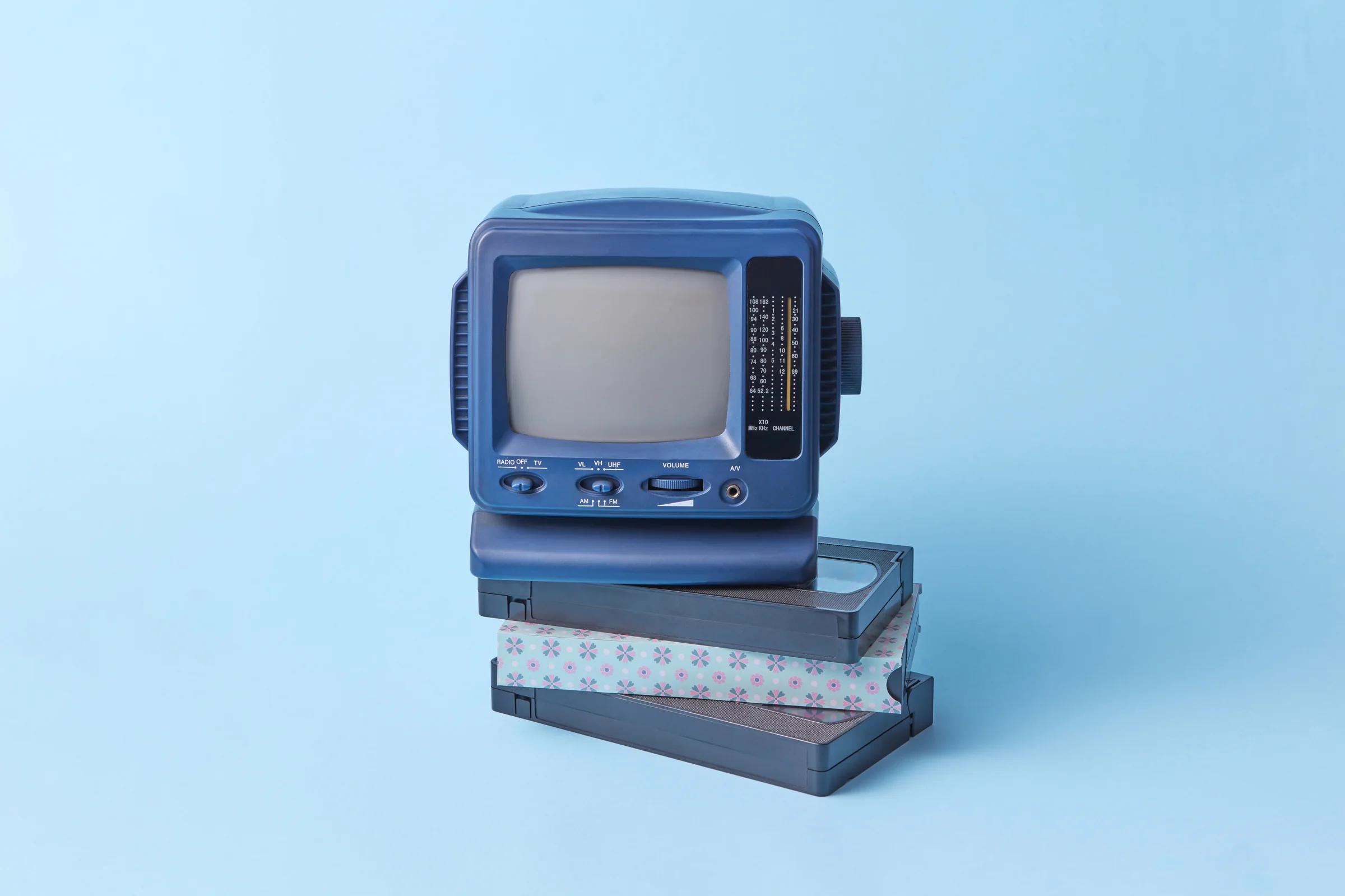 Retro miniature TV on stacked VHS tapes — watching playback at home, the reason people still seek a VCR or digitisation